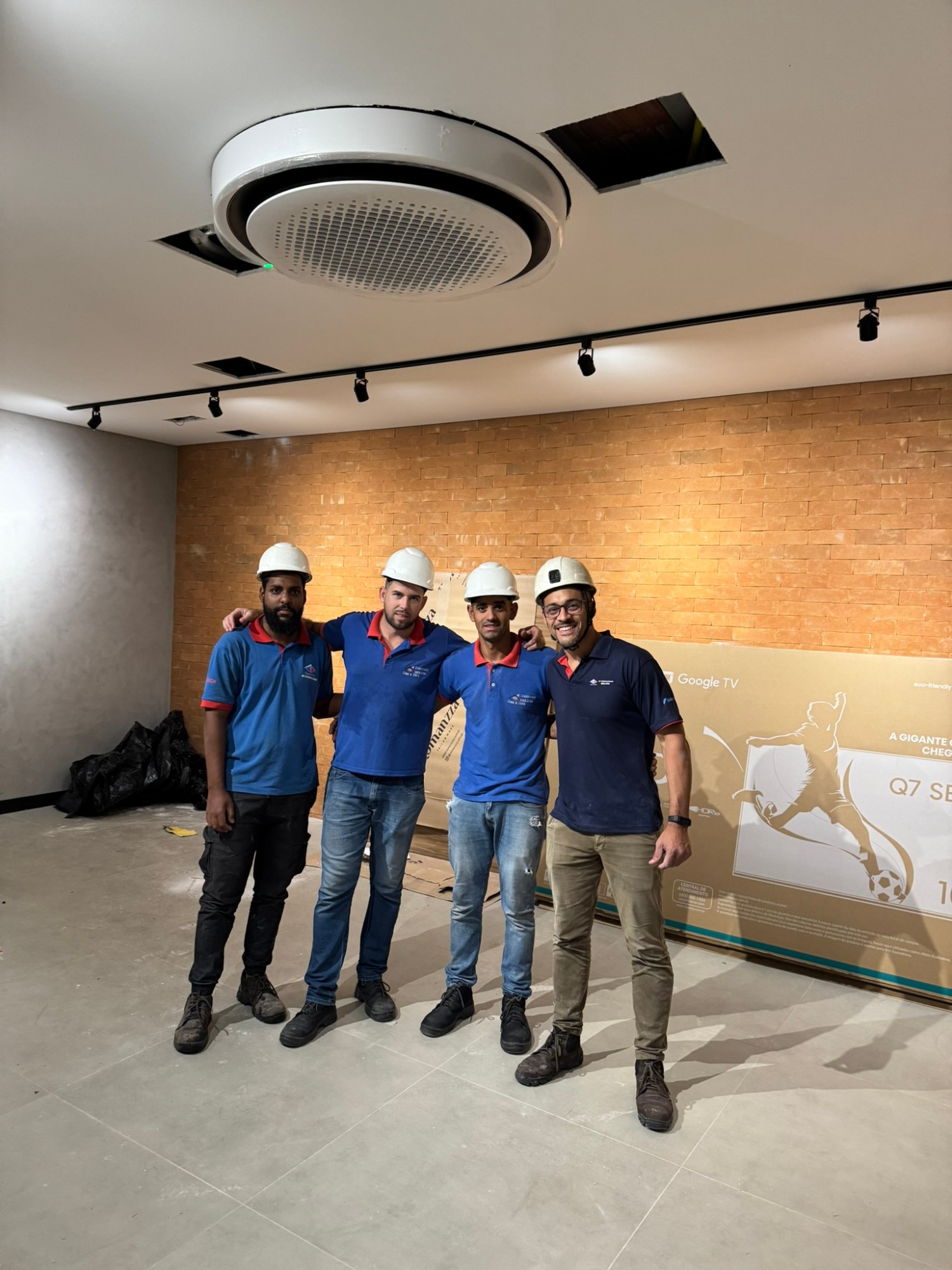 Equipe da Casa e Clima ao lado de uma evaporadora cassete instalada