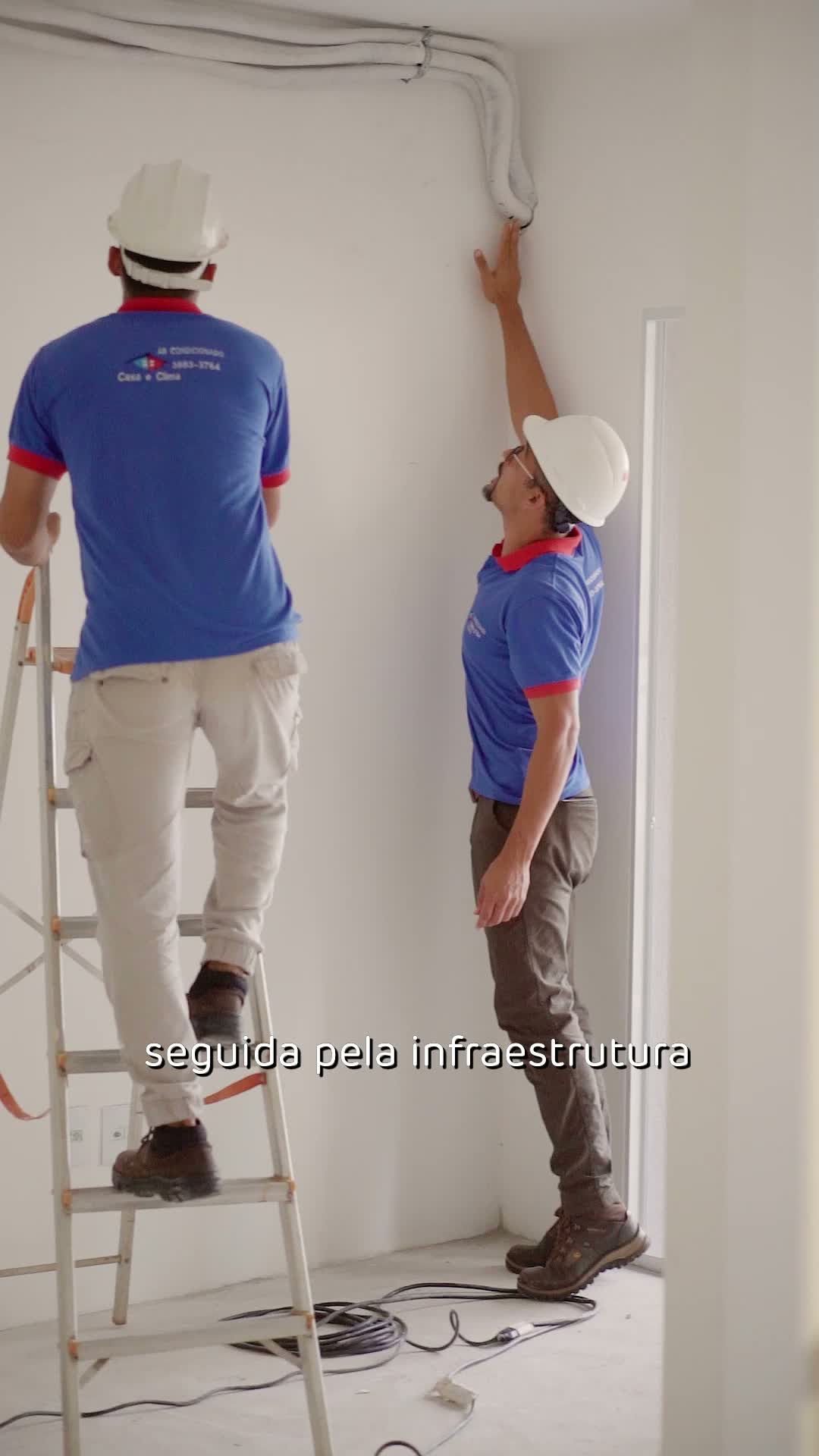 Dois técnicos da Casa e Clima passando a infraestrutura pelo teto e pela parede