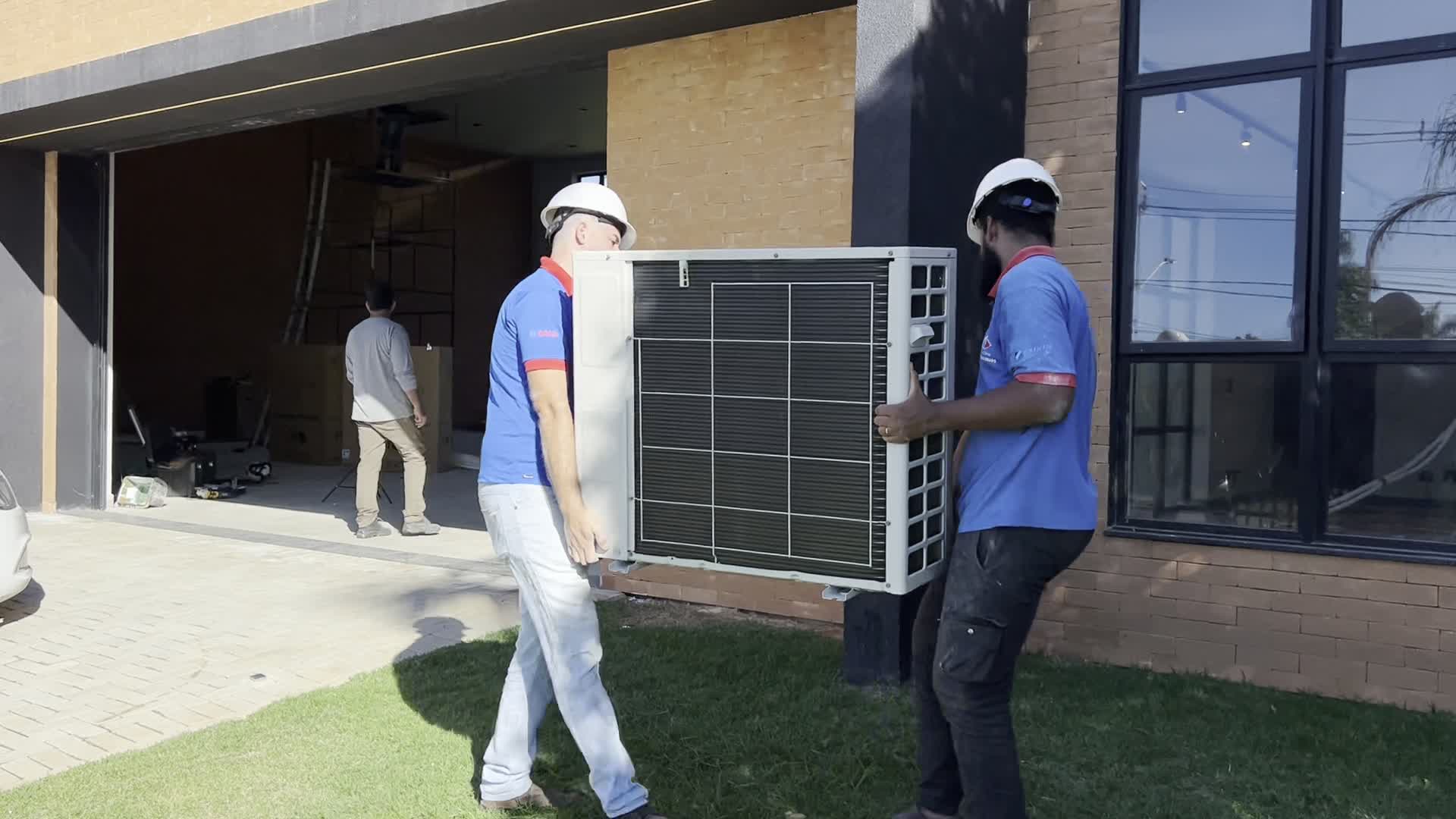 Dois técnicos transportando uma unidade condensadora
